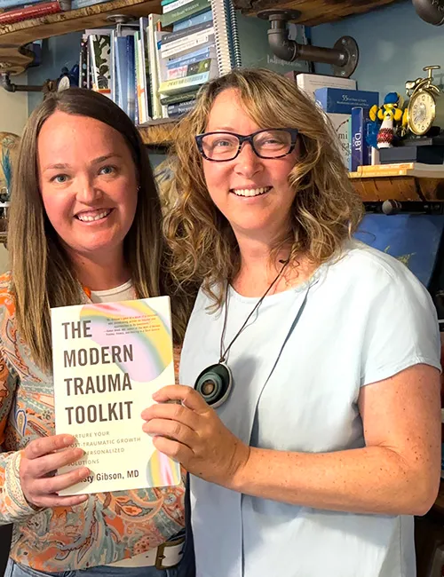 Photo of Lesley Machon (left) and Dr. Christine Gibson (right), both holding Dr. Gibson's book, "The Modern Trauma Toolkit."
