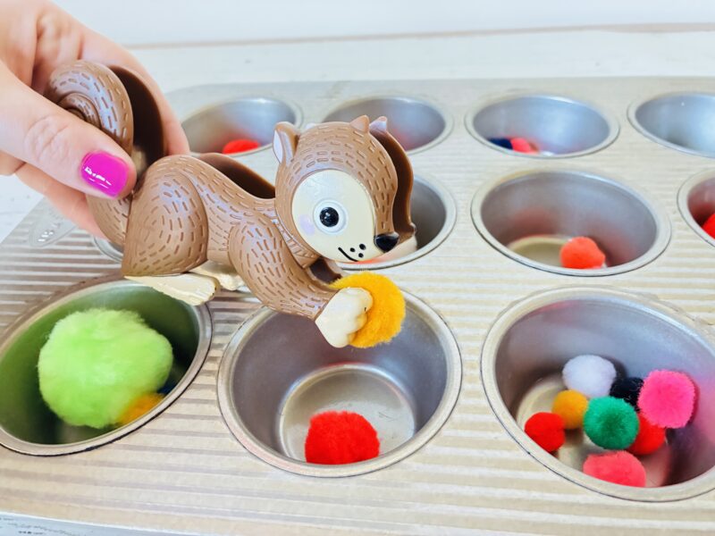 an image of a fine motor activity that has students use toy tweezers to sort pom poms into muffin tins