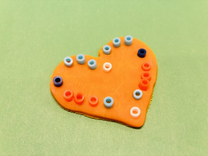 an image of a fine motor activity that involves students placing small beads into playdough to create a mosaic